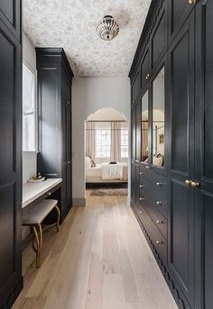 an empty hallway with black cabinets and white sheets on the bed in the background is a large bedroom