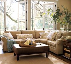 a living room filled with lots of furniture next to a large window covered in windows