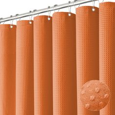 an orange shower curtain hanging on a metal rod with a round button in the center