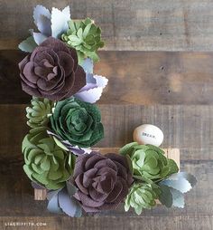 paper flowers arranged in the shape of letter s on a wooden table with an egg