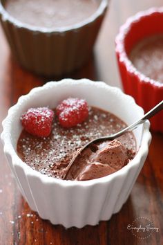 chocolate pudding with raspberries and powdered sugar in small bowls on a wooden table