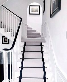 the stairs are lined with black and white rugs, framed pictures on the wall