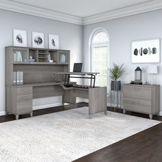 a computer desk sitting on top of a wooden floor next to a white rug in a living room