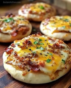 small pizzas with cheese and bacon are on a cutting board, ready to be eaten