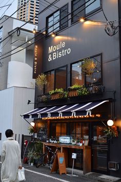 a man walking down the street in front of a building with plants growing on it