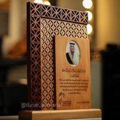 a wooden plaque with an image of a man's head on it, in arabic