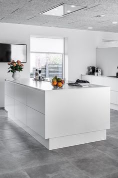 a large kitchen with white cabinets and counter tops, along with an island in the middle