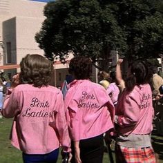 two girls in pink shirts are walking down the street with their hands up to the sky