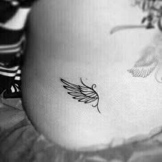 a pregnant woman's belly with an angel wing tattoo on her lower back side