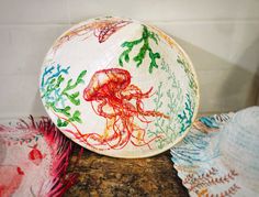 two paper plates with different colored designs on them sitting on a table next to doily