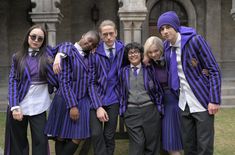 a group of young people dressed in purple and black outfits standing next to each other