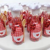 red and white candy jars with wooden spoons in them are lined up on a table