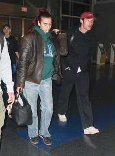 two people walking through an airport carrying bags