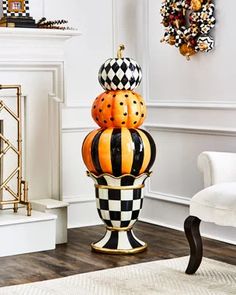 three pumpkins stacked on top of each other in front of a white chair and fireplace