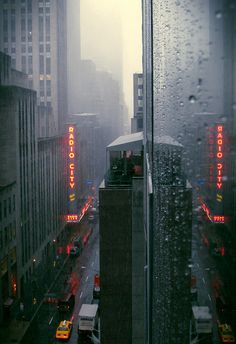 the city is covered in rain and it's lights shine brightly on the buildings