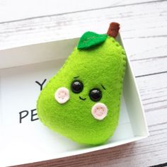 a green stuffed animal in a white box on a wooden table with the word y is for pear