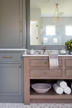 a bathroom with gray cabinets and white towels on the counter top, along with two sinks