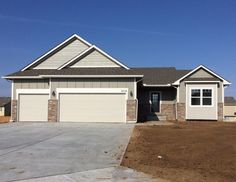 a house that is in the middle of some dirt and has two garages on each side