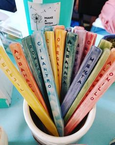 a cup filled with different colored letters sitting on top of a blue tablecloth covered table