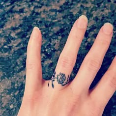 a person's hand with a flower tattoo on their left thumb and the middle finger