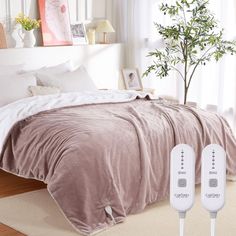 two remote controls are plugged in to a bed with a comforter and pillows