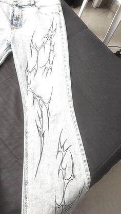 a pair of jeans with an embroidered design on the bottom and side, sitting on a table