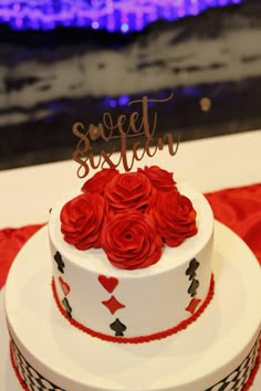 a white cake with red roses on top and the word sweet sixteen spelled in cursive writing