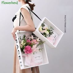 a woman is holding two boxes with flowers in them and the box has an advertisement on it