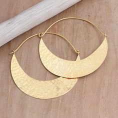 Glamorous and sophisticated, Wayan Karang's hoop earrings are carefully designed with semi-circles of shimmering gold resembling a canoe. Balinese artisans use 22k gold-plated brass to hand craft the earrings, treating the precious metal with a unique hammered finish. Modern Gold Crescent Hoop Earrings, Metal Semi-circle Hoop Earrings For Pierced Ears, Semi-circle Metal Hoop Earrings For Pierced Ears, Metal Semi-circle Hoop Earrings, Gold Hammered Crescent Hoop Earrings, Gold Crescent Hoop Earrings With Hammered Detail, Gold Semi-circle Metal Earrings, Gold Crescent Hammered Earrings, Gold Hammered Crescent Earrings