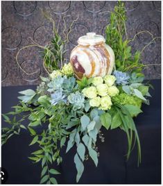 a vase filled with flowers and greenery sitting on top of a black cloth covered table