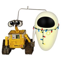 a yellow and black toy car with eyes on it's head next to a white object