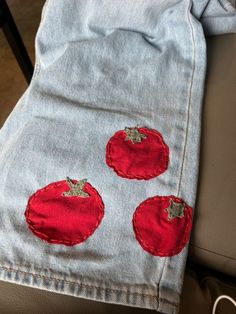 a pair of jeans with embroidered tomatoes on them