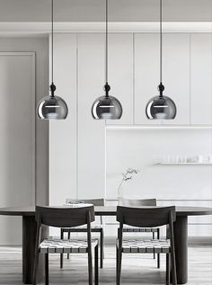 a dining room table with chairs and lights hanging from the ceiling