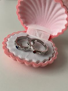 two wedding rings in a pink shell box