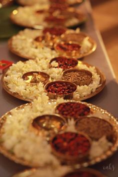 several plates filled with rice and spices on a long table lined with other food items