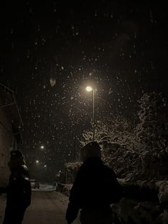 two people walking down a snowy street at night