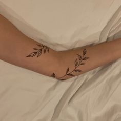 a person laying in bed with a tattoo on their arm