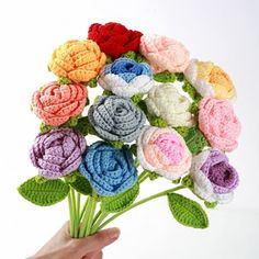 a crocheted bouquet of colorful flowers being held by a person's hand