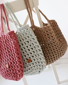 three crocheted bags hanging from a white chair