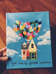 someone is holding up a painting with balloons in the shape of a house that says, you are my great adventure