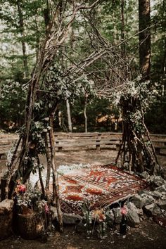 an outdoor area with a rug, trees and flowers on the ground in front of it