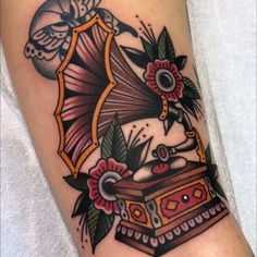 a tattoo design on the leg of a woman's leg with an old record player and flowers