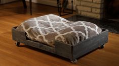 a giraffe print blanket sitting on top of a wooden crate in front of a fireplace