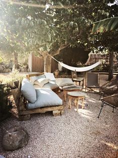 a hammock in the middle of a graveled area with chairs and tables