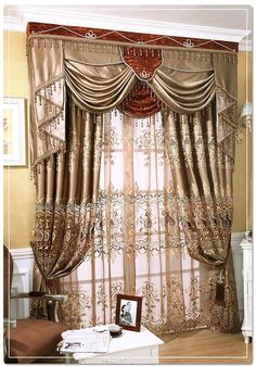 a living room with curtains and pictures on the table in front of it's windows