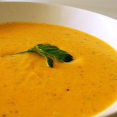 a white bowl filled with soup and garnished with a green leaf