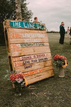 a wooden sign sitting on top of a lush green field