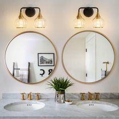 two round mirrors are hanging on the wall above double sinks in this white bathroom with marble countertop