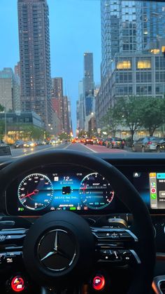 the dashboard of a car with city lights in the backgrouund and skyscrapers in the background