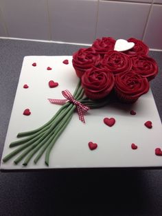 a white cake with red roses on top and hearts in the middle, sitting on a counter